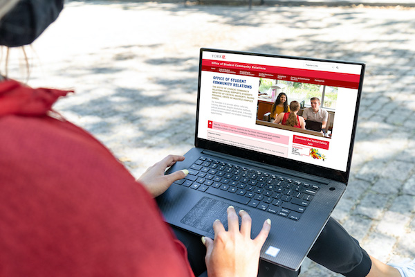 A person looking at Office of Student Community Relations (OSCR) website on her laptop